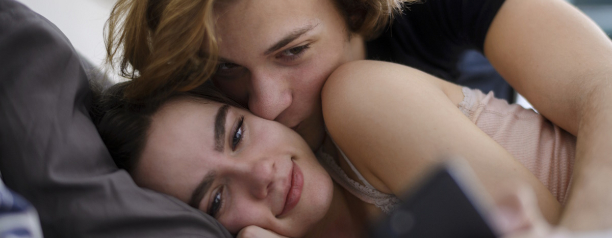 Junges Paar liegt verliebt im Bett und schmust