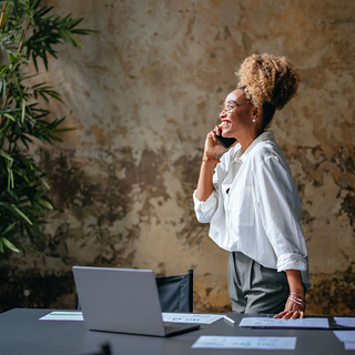L&auml;chelnde Gesch&auml;ftsfrau, die auf einem Mobiltelefon spricht