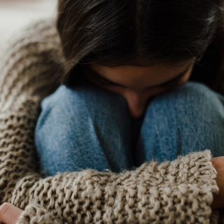 Teenager-M&auml;dchen sitzt auf dem Boden mit dem Kopf auf den Knien