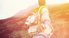 Das Bild zeigt ein Paar das Hand in Hand in der Landschaft steht. 