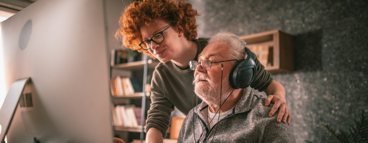Gro&szlig;vater und Enkel sitzen zu Hause am Tisch und benutzen den Computer