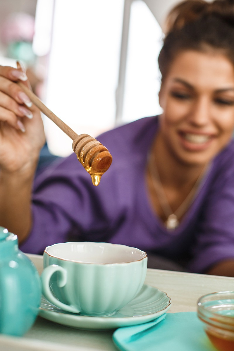 Frau l&auml;sst Honig in den Tee flie&szlig;en