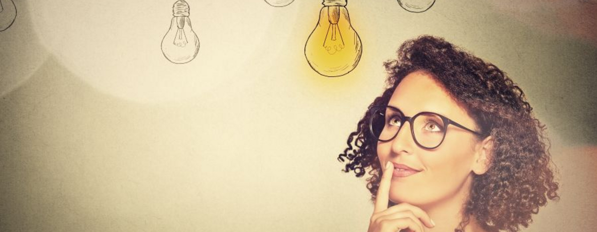 Ein Bild einer Frau die nachdenklich in die Ferne schaut, &uuml;ber ihr eine leuchtende Gl&uuml;hlampe.