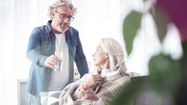 Mann reicht einer &auml;lteren Frau ein Glas Wasser