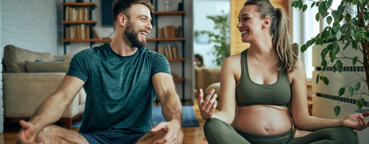 schwangere Frau macht zusammen mit ihrem Mann Yoga
