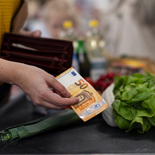Nahaufnahme einer Frau, die an der Kasse im Supermarkt Geld gibt