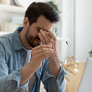 Mann vor dem PC reibt sich die Augen