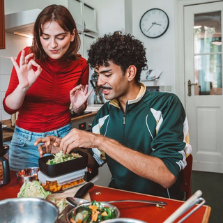 Junge Frau und Mann naschen Mahlzeit aus Brotdosen mit hausgemachter zubereiteter Mahlzeit
