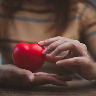 Eine junge Frau, die ein Herz in den H&auml;nden h&auml;lt.