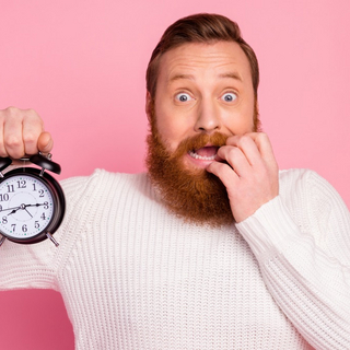 &Auml;ngstlicher Mann mit Wecker in der Hand