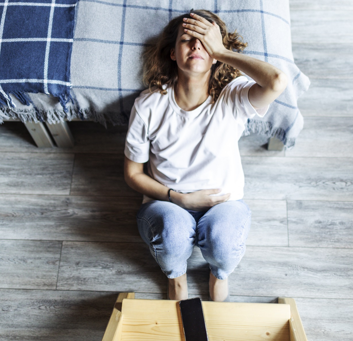 Junge Frau leidet an Ersch&ouml;pfung und M&uuml;digkeit und h&auml;lt sich die Hand an den Kopf
