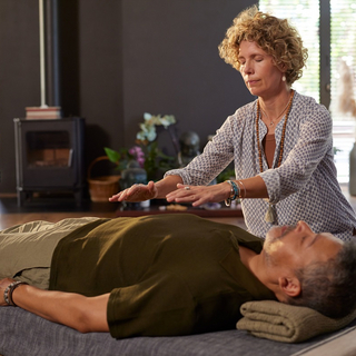 Eine Anthroposophin behandelt einen Patienten, der auf einer Liege liegt.