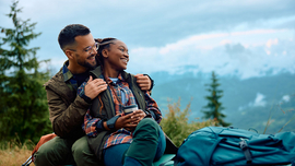 Ein Paar sitzt auf einer Wiese in den Bergen