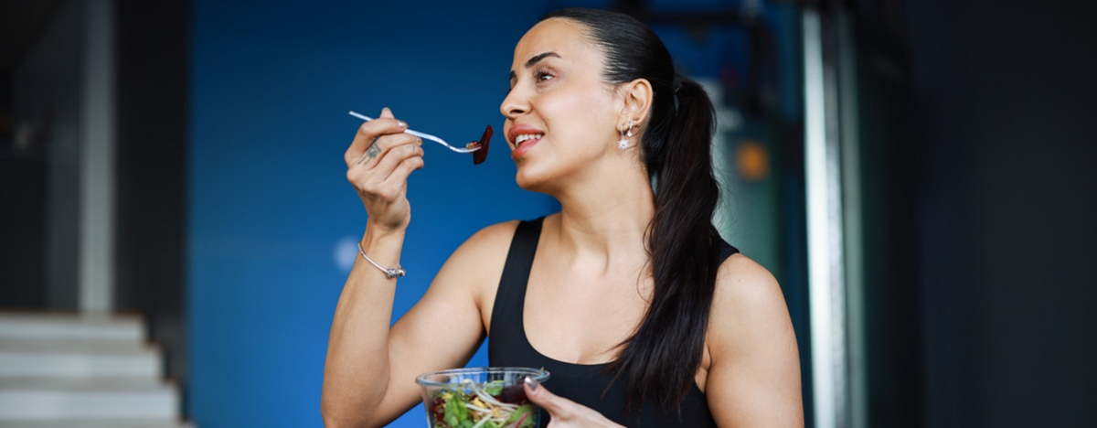 Eine junge Frau isst einen Salat nach dem Training.