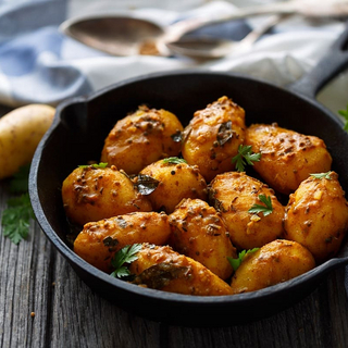 Nahaufnahme von Bombay Kartoffeln in einem gusseisernen Sch&uuml;ssel, lecker angerichtet.