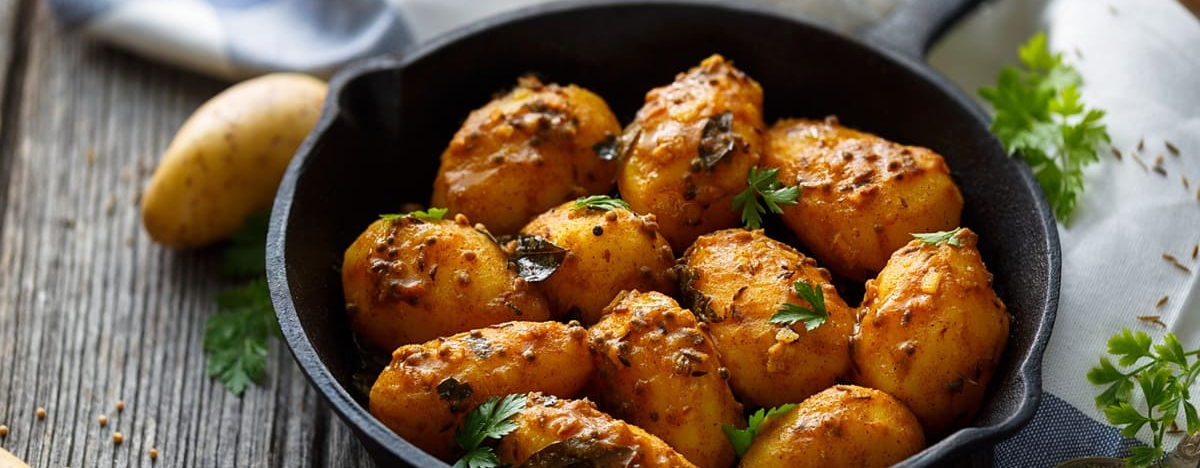 Nahaufnahme von Bombay Kartoffeln in einem gusseisernen Sch&uuml;ssel, lecker angerichtet.