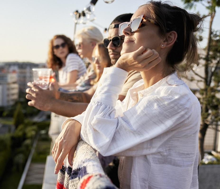 Junge Erwachsene schauen von einer Dachterrasse in die Sonne