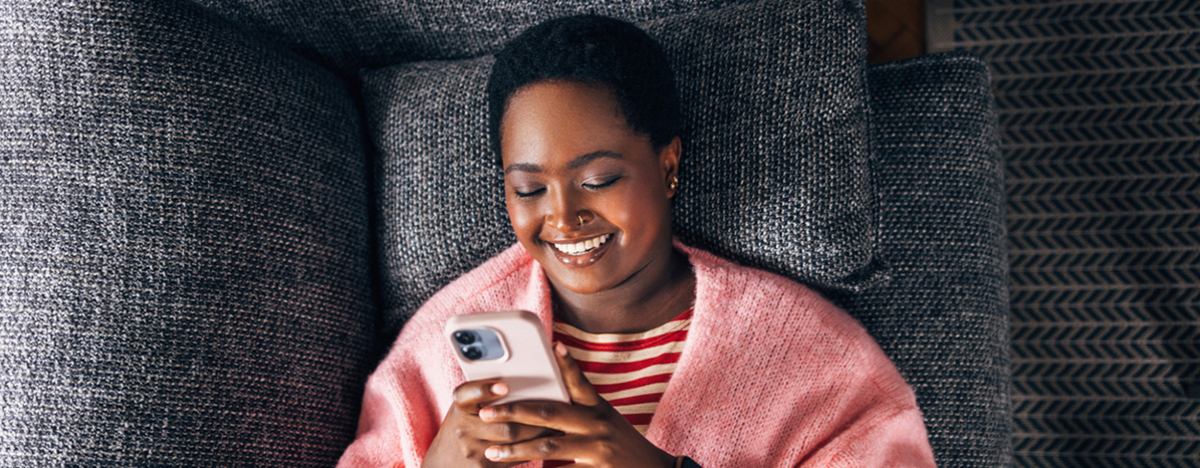 M&auml;dchen liegt auf Sofa und sieht auf ihr Handy