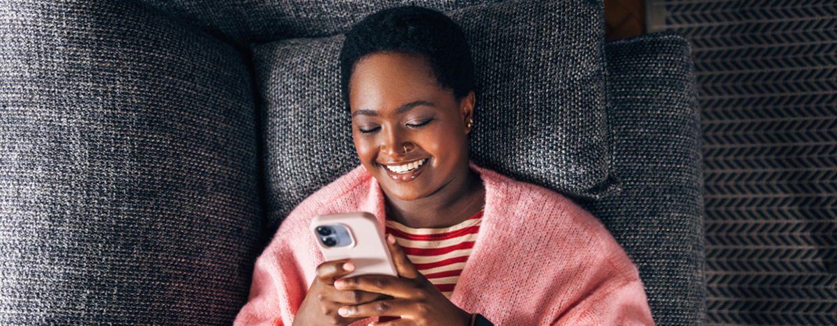 M&auml;dchen liegt auf Sofa und sieht auf ihr Handy
