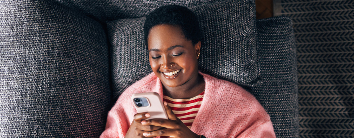 M&auml;dchen liegt auf Sofa und sieht auf ihr Handy