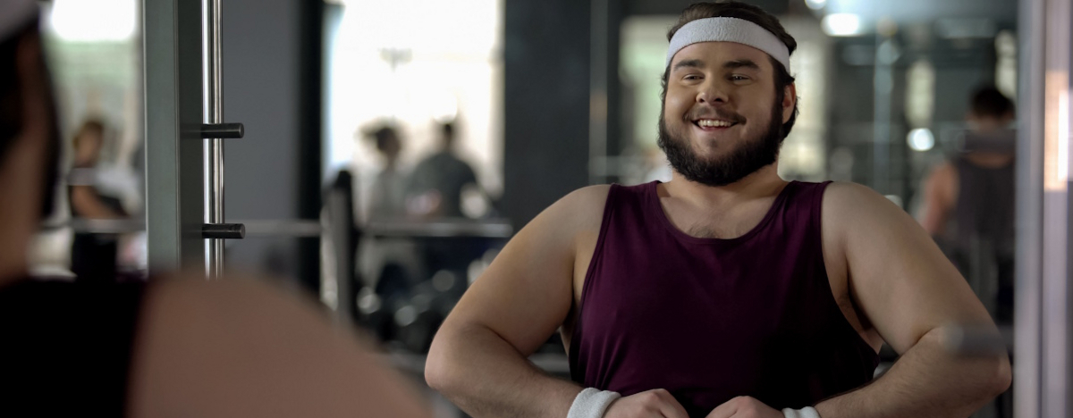 Dicker Mann macht Krafttraining im Fitnessstudio