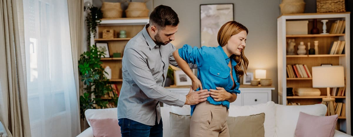 Eine Frau mit schmerzverzerrtem Gesicht hat einen Bandscheibenvorfall.