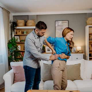 Eine Frau mit schmerzverzerrtem Gesicht hat einen Bandscheibenvorfall.