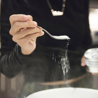 Eine Person, die Natron in eine Sch&uuml;ssel zum Backen gibt.