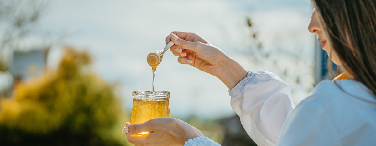 Frau zeigt ein Glas Honig in der Natur