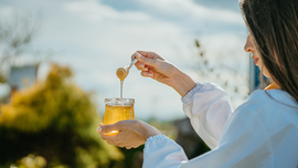 Frau zeigt ein Glas Honig in der Natur