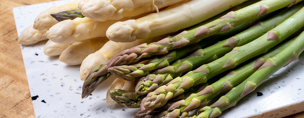 Wei&szlig;er und gr&uuml;ner Spargel auf einem K&uuml;chenbrett