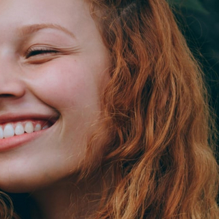 Junge Frau mit roten Haaren l&auml;chelt