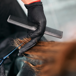 Friseur schneidet die Haarspitzen einer Frau