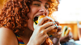 Frau bei&szlig;t in einen Burger