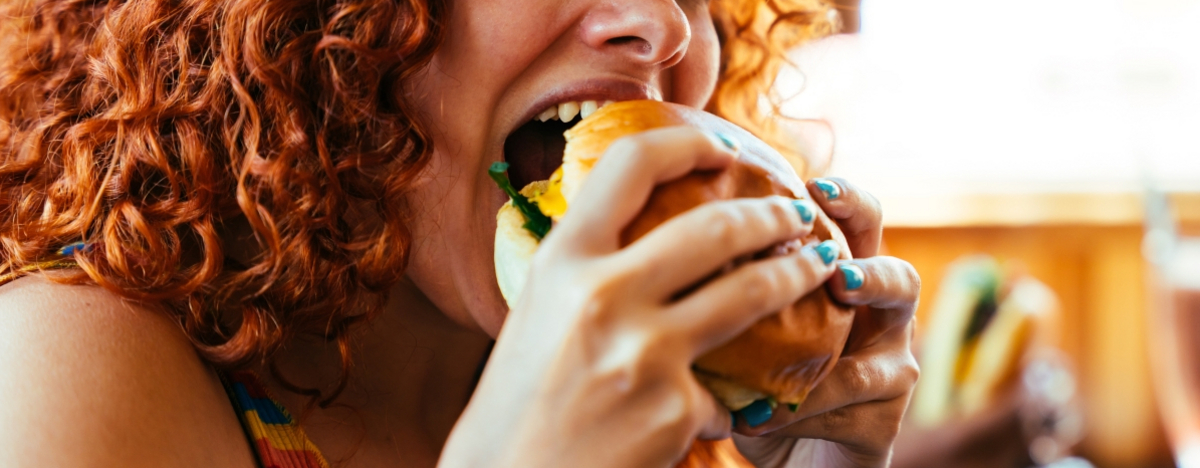 Frau bei&szlig;t in einen Burger